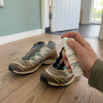 Schoenenspray wordt gebruikt op een paar gedragen sportschoenen in de gang